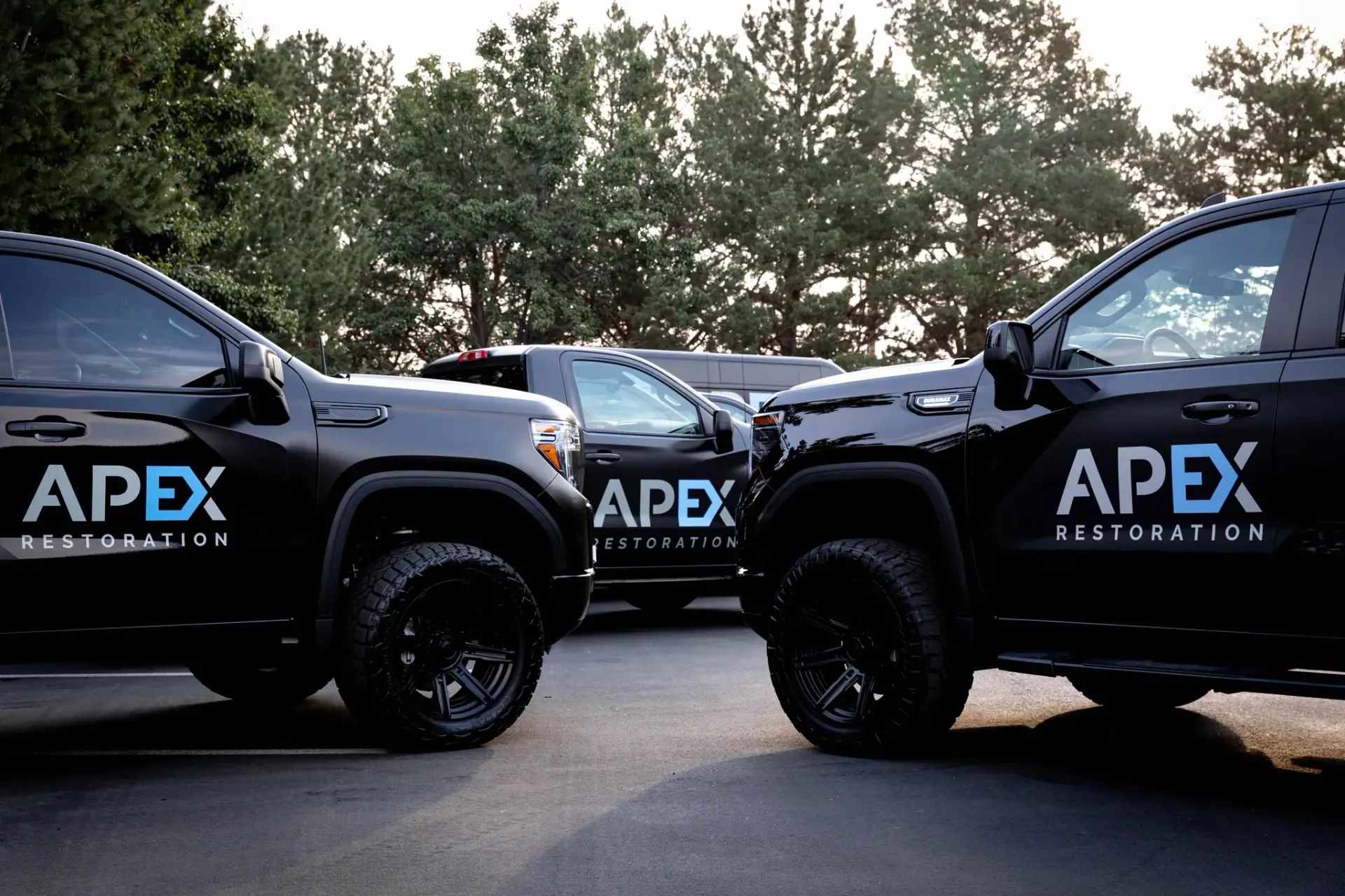 Black Apex Restoration pickup trucks parked nose to nose in a lot, water damage restoration in Idaho and Eastern Washington
