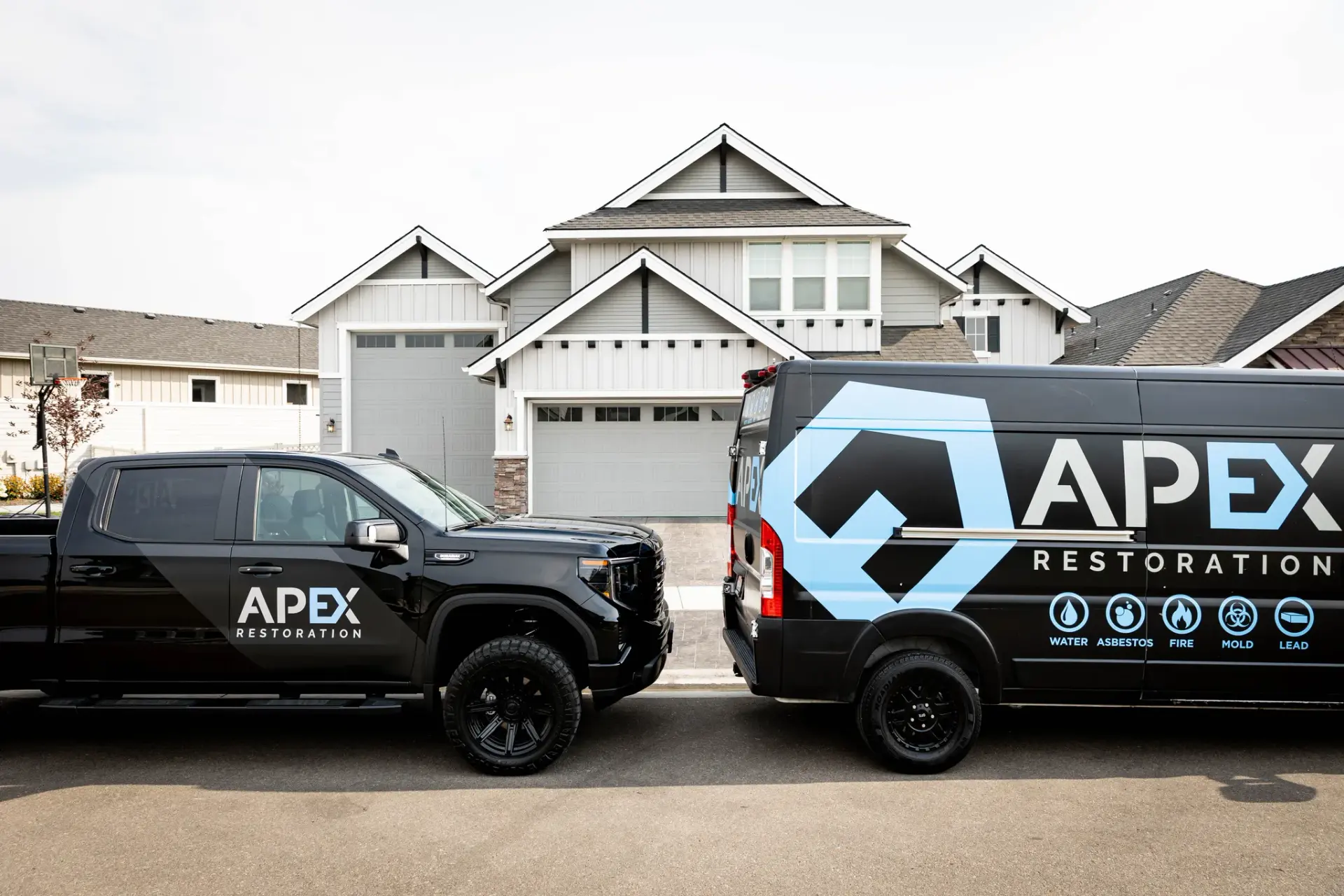 Apex Restoration truck and van parked outside a client's home